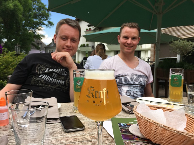 Zwei Wanderer im Biergarten, im Vordergrund ein Bier.