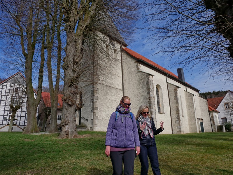Kirche St. Urban im Hintergrund, im Vordergrund zwei Wanderer