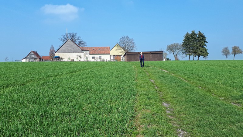 Das Bild zeigt Meike auf einem Wiesenweg, im Hintergrund ist ein Bauernhof zu sehen.