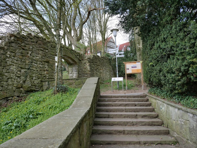 Das Bild zeigt Stufen, die vorbei führen an Mauerresten der Burg Tecklenburg. Im Hintergrund ist die Jugendherberge Tecklenburg zu sehen.