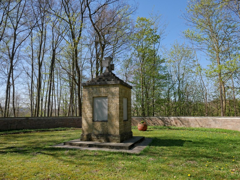 Das Bild zeigt die zentrale Stele des Ehrenmals, die von einer ringförmigen Ziegelmauer umgeben ist.