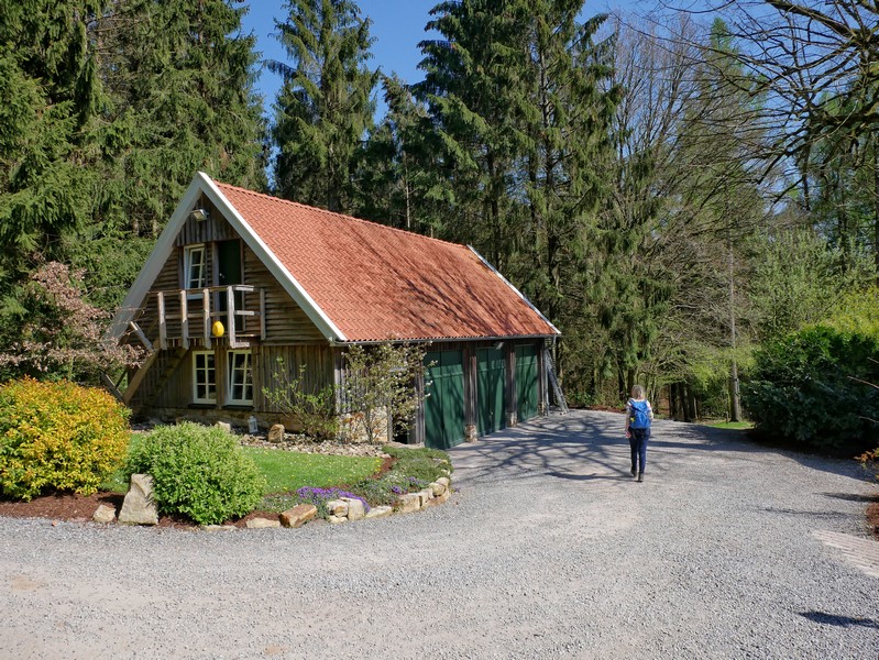 Das Bild zeigt ein kleineres Holzhaus und danebn Meike auf dem TERRA.track Borgloher Schweiz.