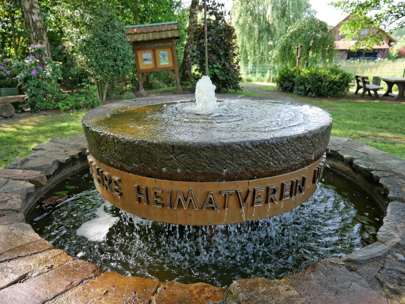 Das Bild zeigt den Brunnen auf dem Dorfplatz in Ueffeln.